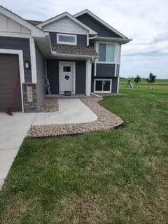 Modern two-story house with a landscaped front yard and concrete walkway.